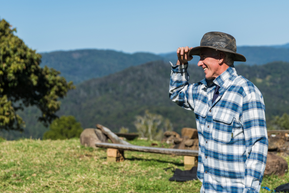 man in a hat looking out over a green landscape